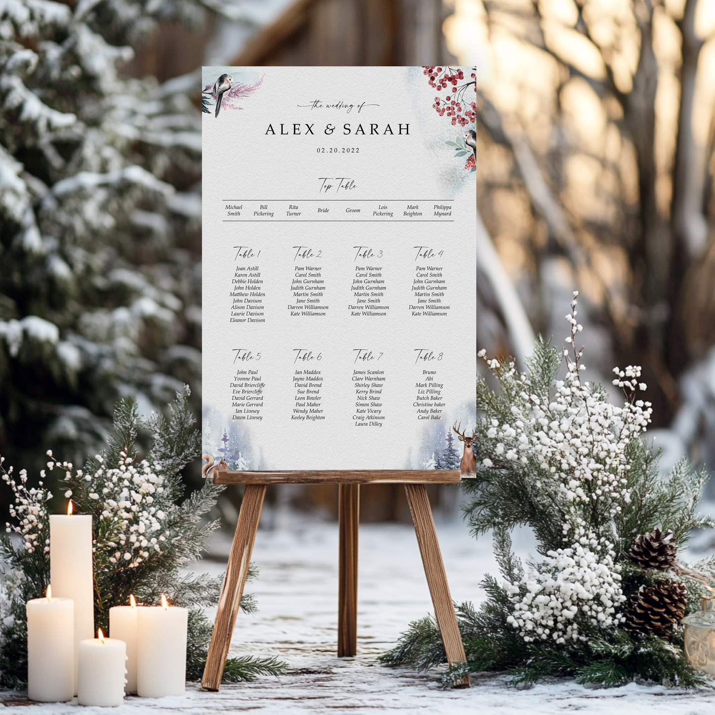 A seating plan for a wedding reception is displayed on an easel, surrounded by candles and pine cones, with a snowy forest in the background.
