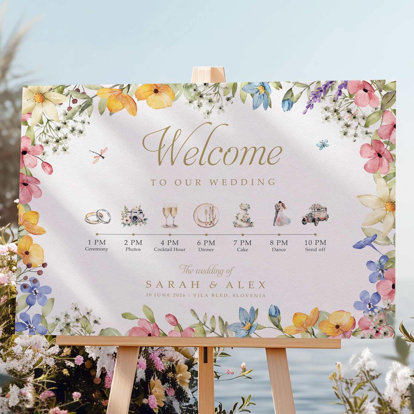 Wedding welcome sign on an easel with floral decorations and a scenic background.