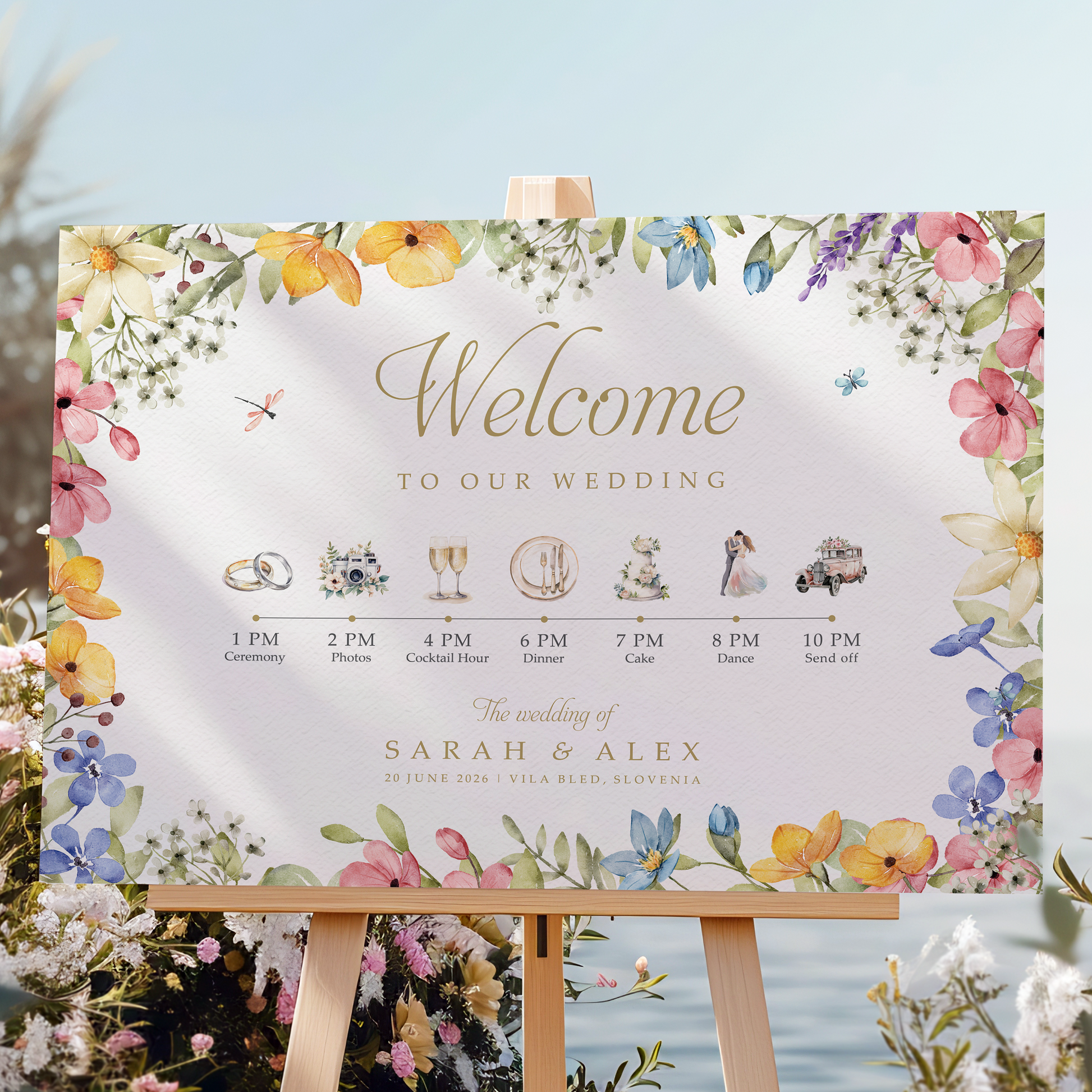 Wedding welcome sign on an easel with floral decorations and a scenic background.
