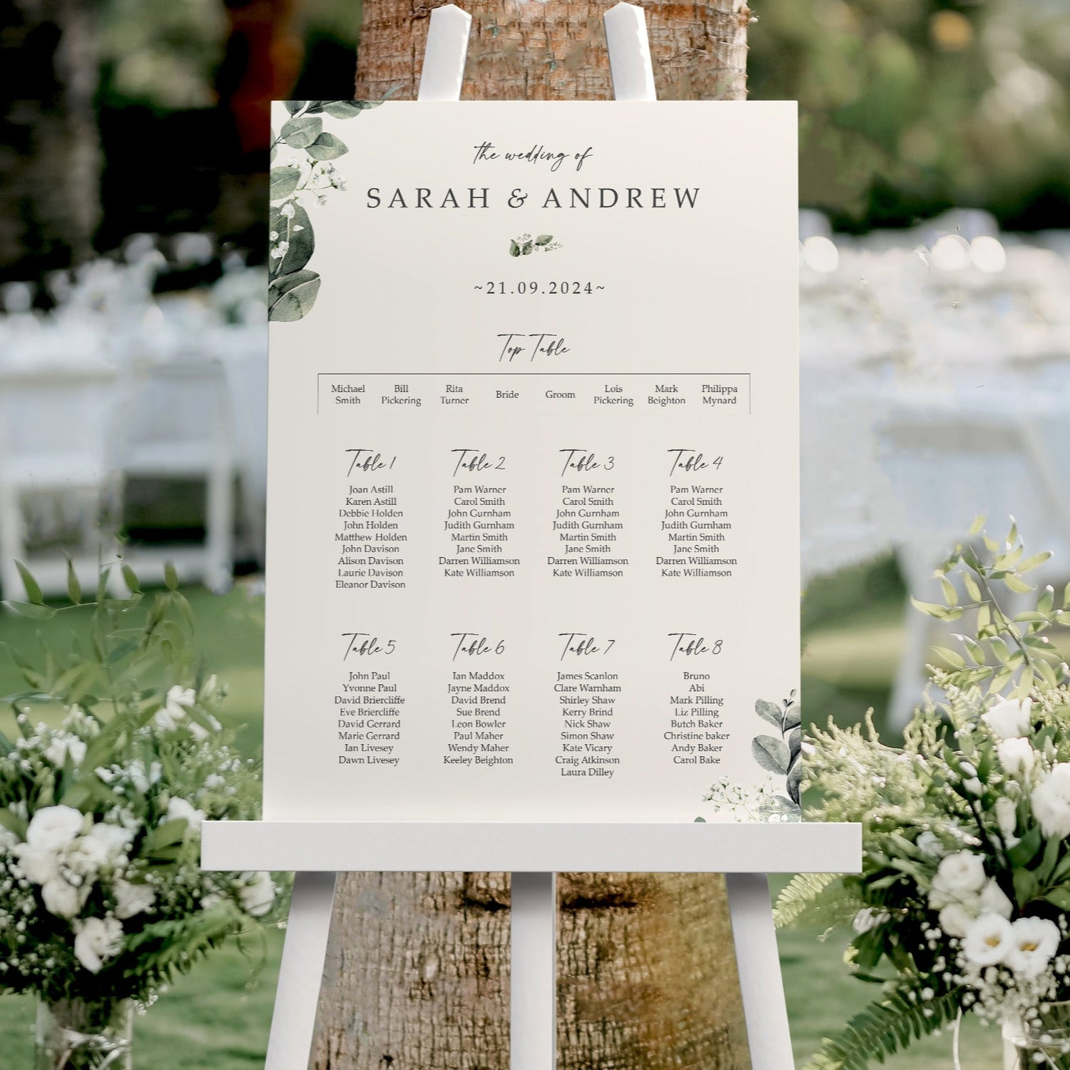 gypsophila baby's breath Wedding seating chart on an easel with floral arrangements and tables in the background