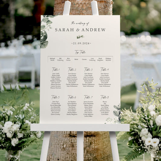 gypsophila baby's breath Wedding seating chart on an easel with floral arrangements and tables in the background
