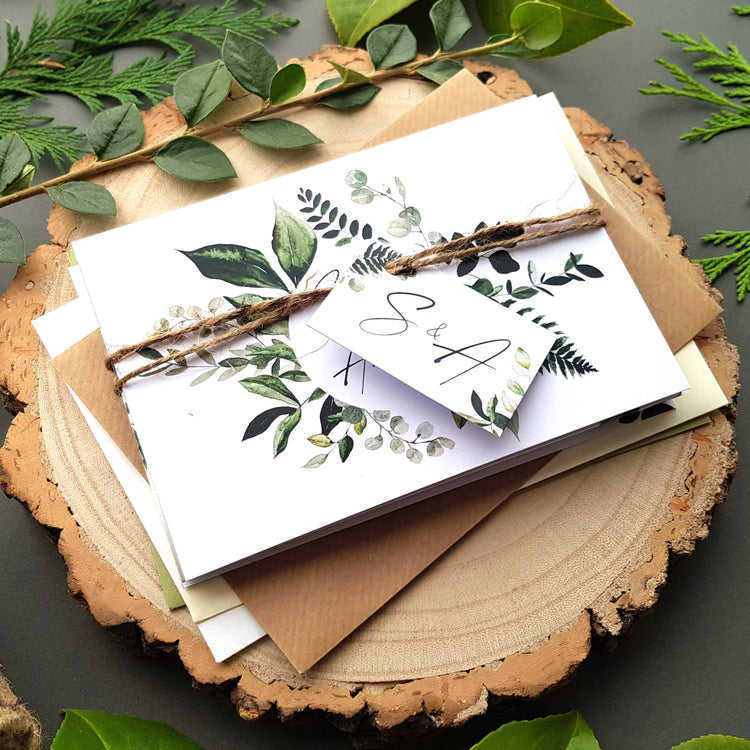 Greenery wedding invitations set with personalised tag, rustic twine and a choice of envelopes. Featuring an array of leafy greenery with iniitals in the middle and calligraphy font