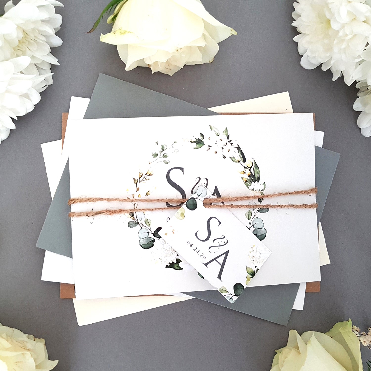 Wedding invitation set featuring an array of white florals with greenery complete with personalised tag, rustic twine and a choice of envelopes. Wedding invite come as a 4 panel concertina printed double sided with gift poem, menu, menu choices and finer details.